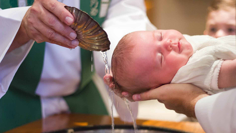 Catholic baptism ceremony with priest blessing a child