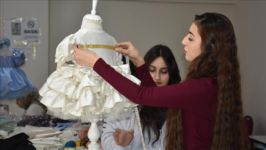 Garment specialist inspecting fabric, stitching, and layered skirt construction of a children's occasion dress.