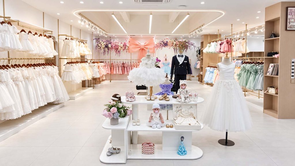 Children's clothing showroom in Guangzhou displaying girls' dresses, boys' formalwear, and baby clothing for wholesale buyers.